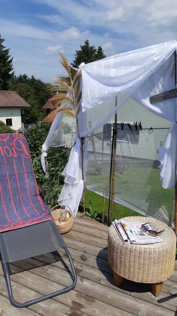 Transparenten Vorhangbahnen an einzelnen Bambusstangen bieten einen Sichtschutz am Pool.