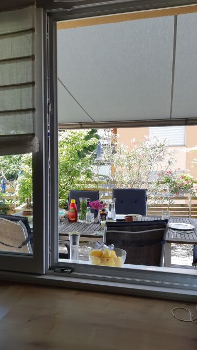 Von der Küche sieht man durch ein Fenster auf die Terrasse. Zu Mittag wird das Fenster zur Durchreiche. Die neue Markise spannt sich über den Tisch, beschattet aber auch das Küchenfenster. 