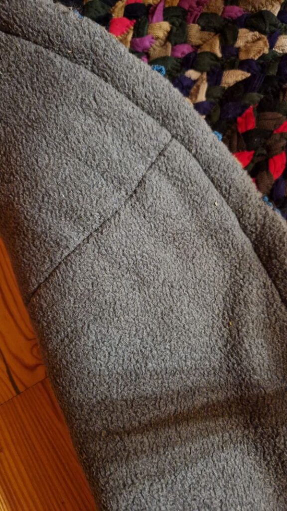 Die Rückseite des DIY Teppich aus aneinander gesteppten Flechtschnüren ist eine alte Kuscheldecke.