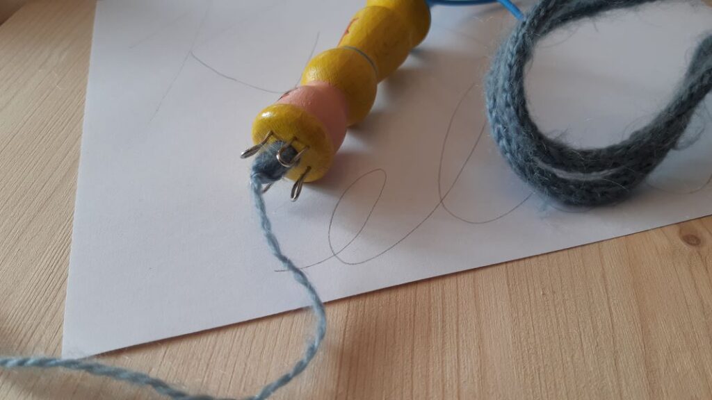 Damit ich weiß ob der gelieselte Strickschlauch schon lang genug ist, lege ich ihn immer wieder mal zur Probe auf den Schriftzug.