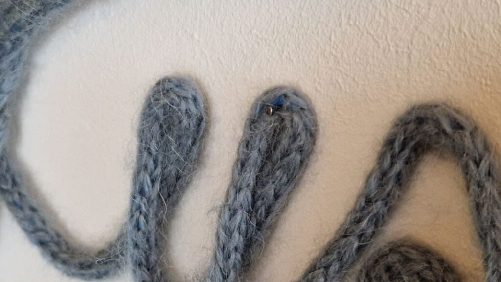 Der DIY Schriftzug aus Wolle wird am besten mit kleinen Nägeln an der Wand befestigt.