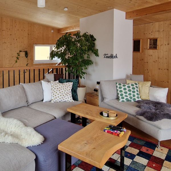 DIY Schriftzug aus Wolle als Wanddekoration im Wohnzimmer neben der Couch.