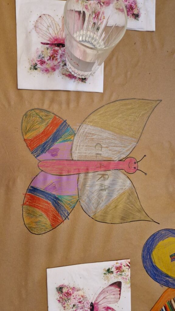 Esstisch mit Packpapier mit ausgemaltem Schmetterling.