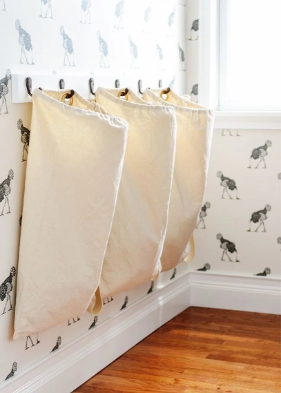 Große Stoffbeutel an Wandhaken können im Kleinkindalter alles mögliche an Spielsachen sammeln. Schnelles Aus- und Einräumen inklusive. Später sammeln sie Schmutzwäsche. Oder Sportequipment oder die Haken werden, wenn es ein Mädchenzimmer ist, für Schmuck genutzt.