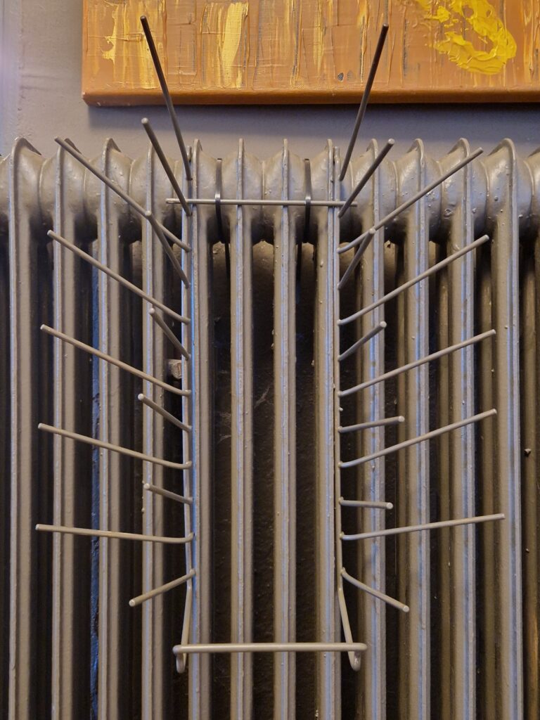 Der Tellerhalter aus unserem alten Geschirrspüler wurde in der selben Farbe gestrichen wie der Heizkörper und mit Kabelbindern befestigt.