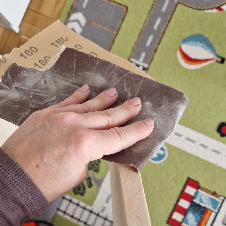Mit der Hand wird die Holzkante geschliffen.