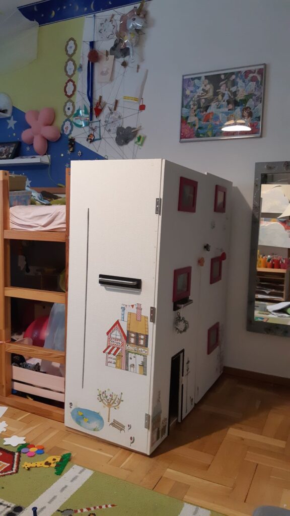 Ein DIY Barbiehaus aus Holz im Kinderzimmer vor dem Hochbett.