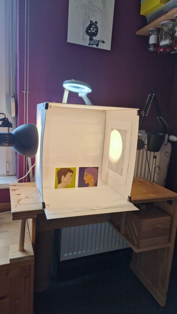 Hier siehst Du mein erstes Fotoobjekt in der DIY Fotobox (Lichtbox): Zwei kleine Holzquadrate auf denen ich gerade Gesichter im Profil male.