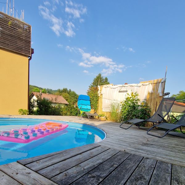 Aufstellpool mit Holzterrasse, drei Liegestühlen und Sichtschutz aus Bambusstangen und altem Vorhang.