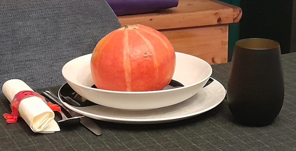 Ein schwarzes Tischtuch mit grünem Karo, schwarz-weißes Geschirr, schwarz-goldene Trinkbecher und der DIY Spinnen-Serviettenring machen Lust auf eine Halloween Party.