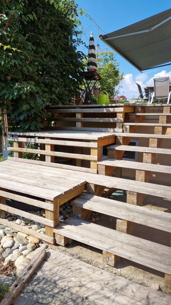 Holzstiege von der Terrasse in den Garten mit zwölf Stufen und drei Sitzpodesten.